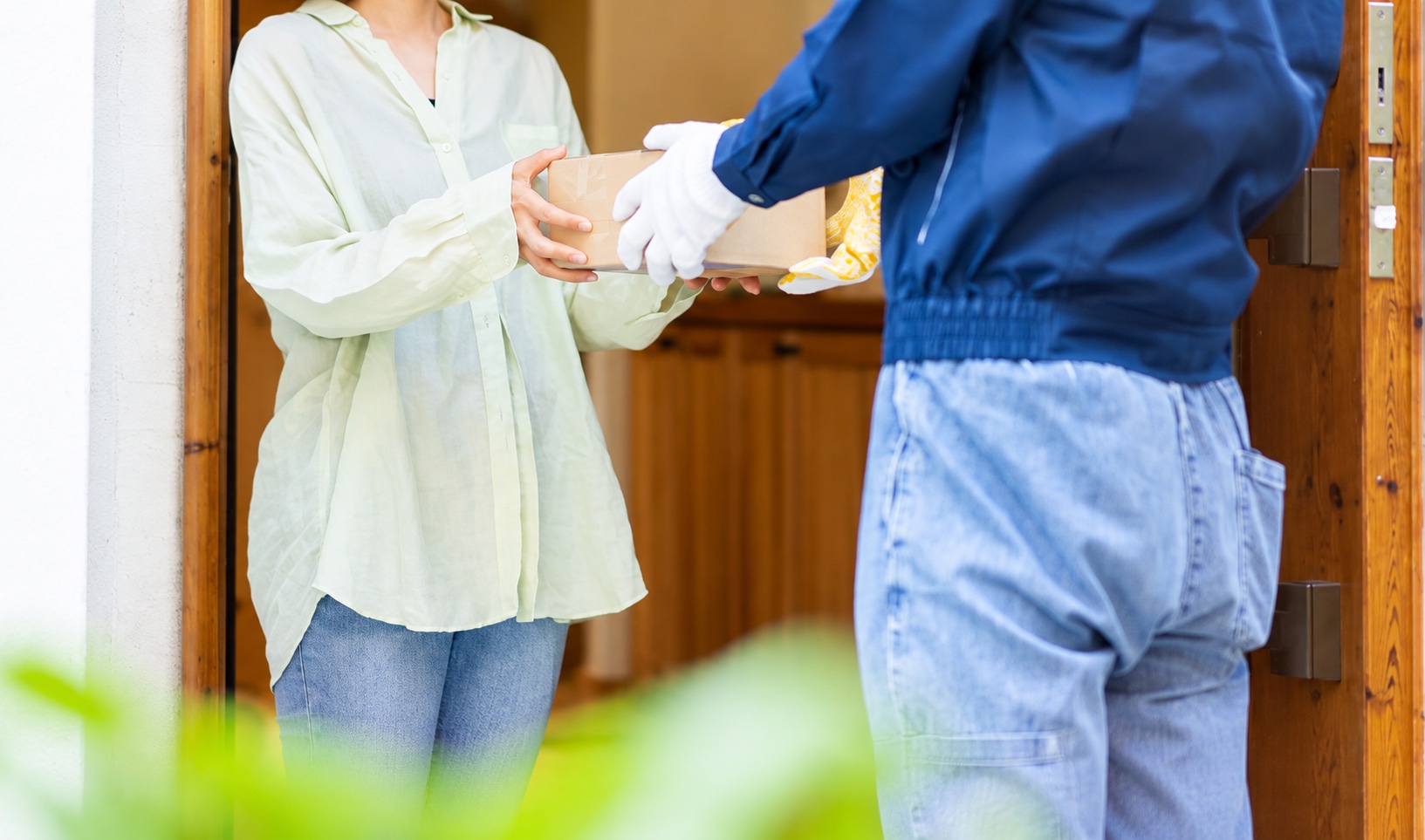 A parcel being handed over at a wooden doorway